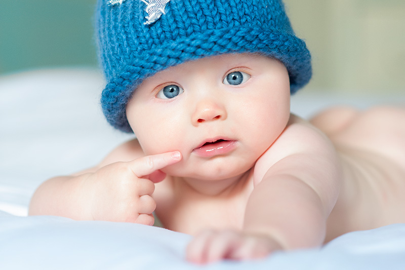 A baby wearing a blue knitted hat in a personal branding headshot.