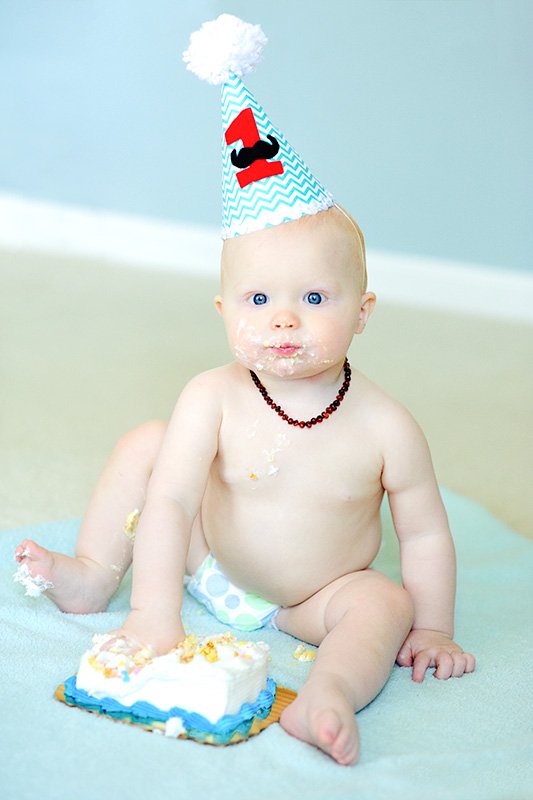 A baby wearing a birthday hat captured in a professional photographer's headshot.