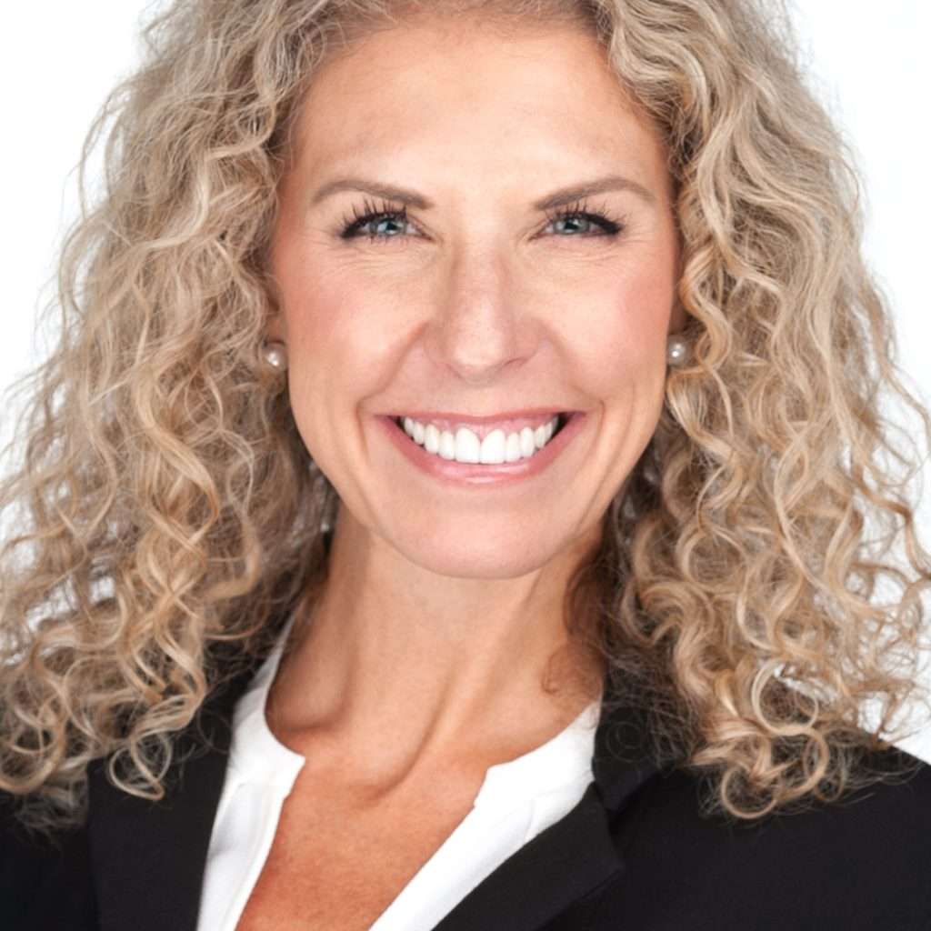 A smiling woman with curly hair in a business suit, captured by Sarah Anne Wilson Photography in Cary, North Carolina. The image showcases a professional look suitable for corporate headshots or business headshots