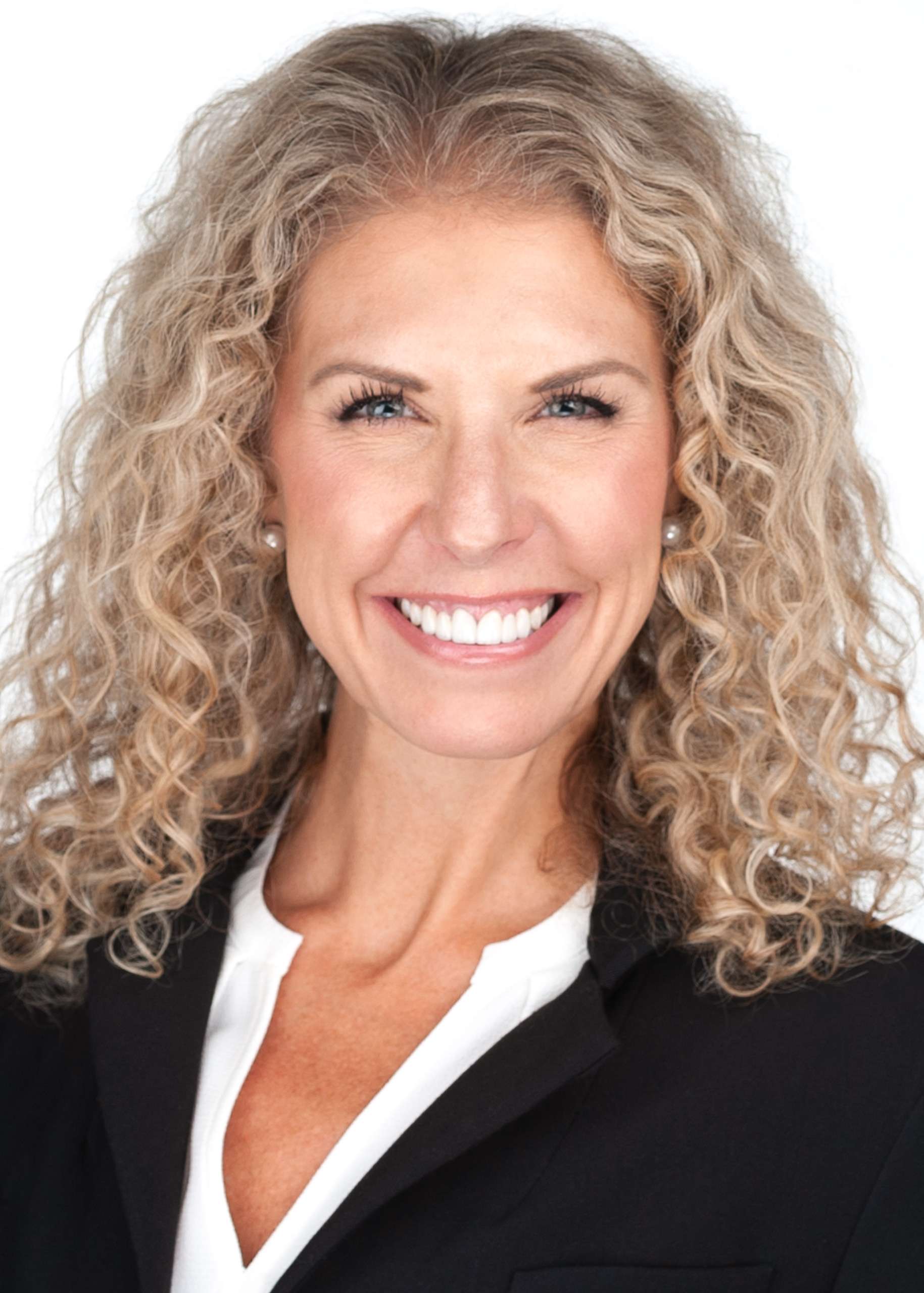A smiling woman with curly hair in a business suit, captured by Sarah Anne Wilson Photography in Cary, North Carolina. The image showcases a professional look suitable for corporate headshots or business headshots