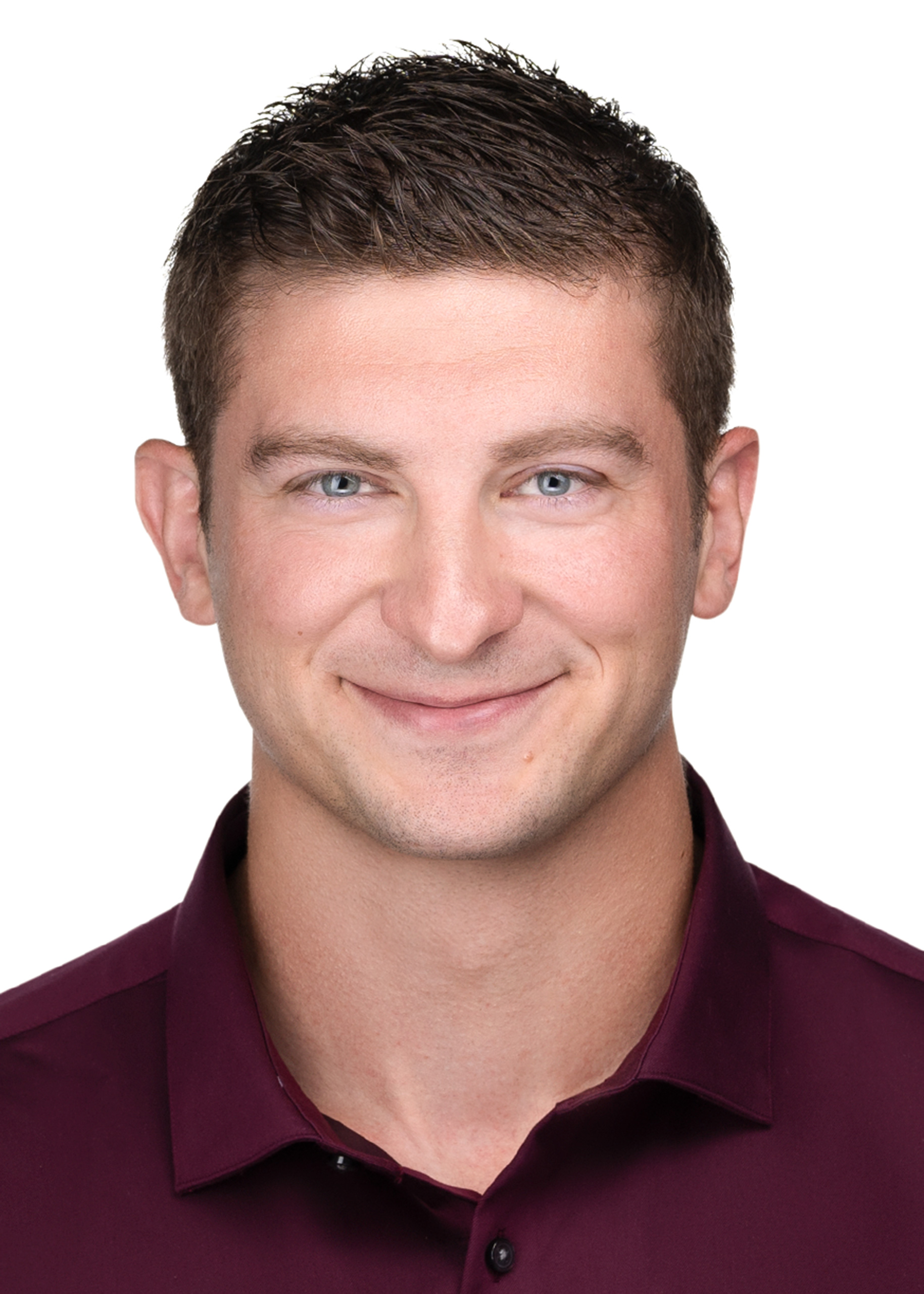 A man in a maroon shirt is smiling for his corporate headshot, showcasing his personal branding.