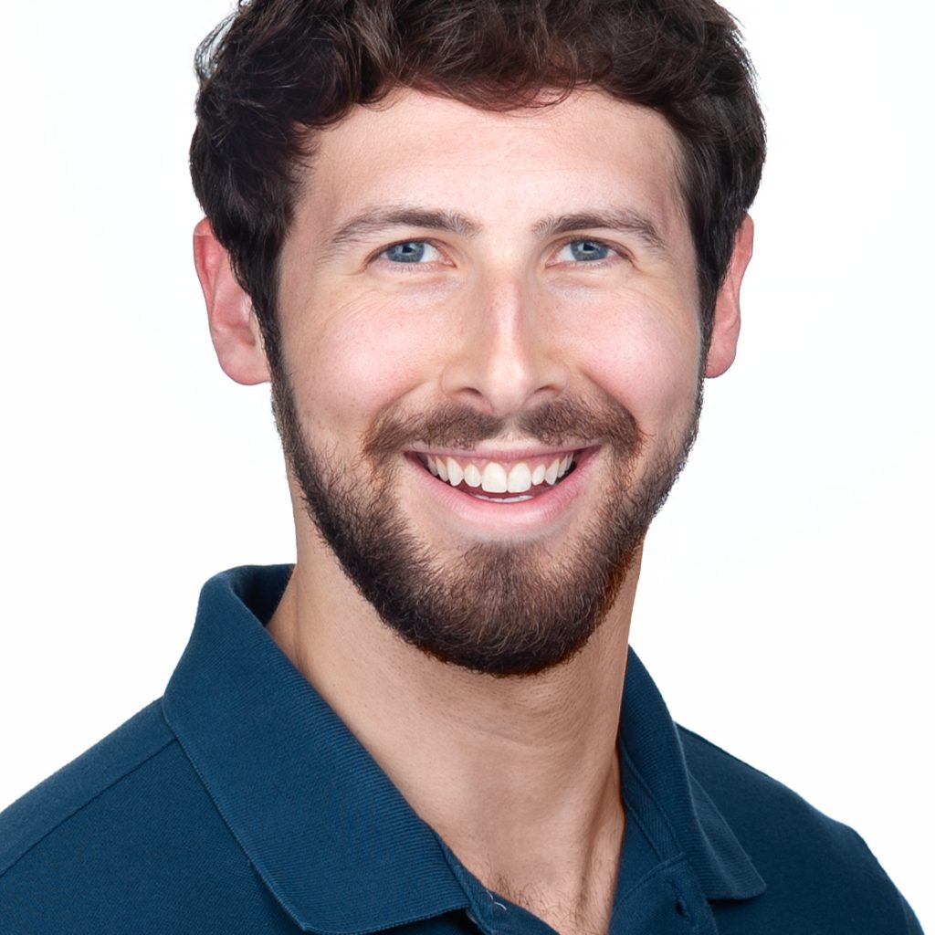 A young man with a beard wears a teal green shirt for a corporate headshots session in the studio of Sarah Anne Wilson