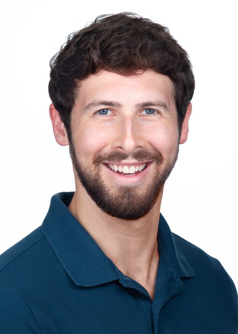 A young man with a beard wears a teal green shirt for a corporate headshots session in the studio of Sarah Anne Wilson