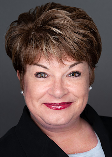 A woman in a black jacket poses for professional headshots taken by a skilled corporate photographer.