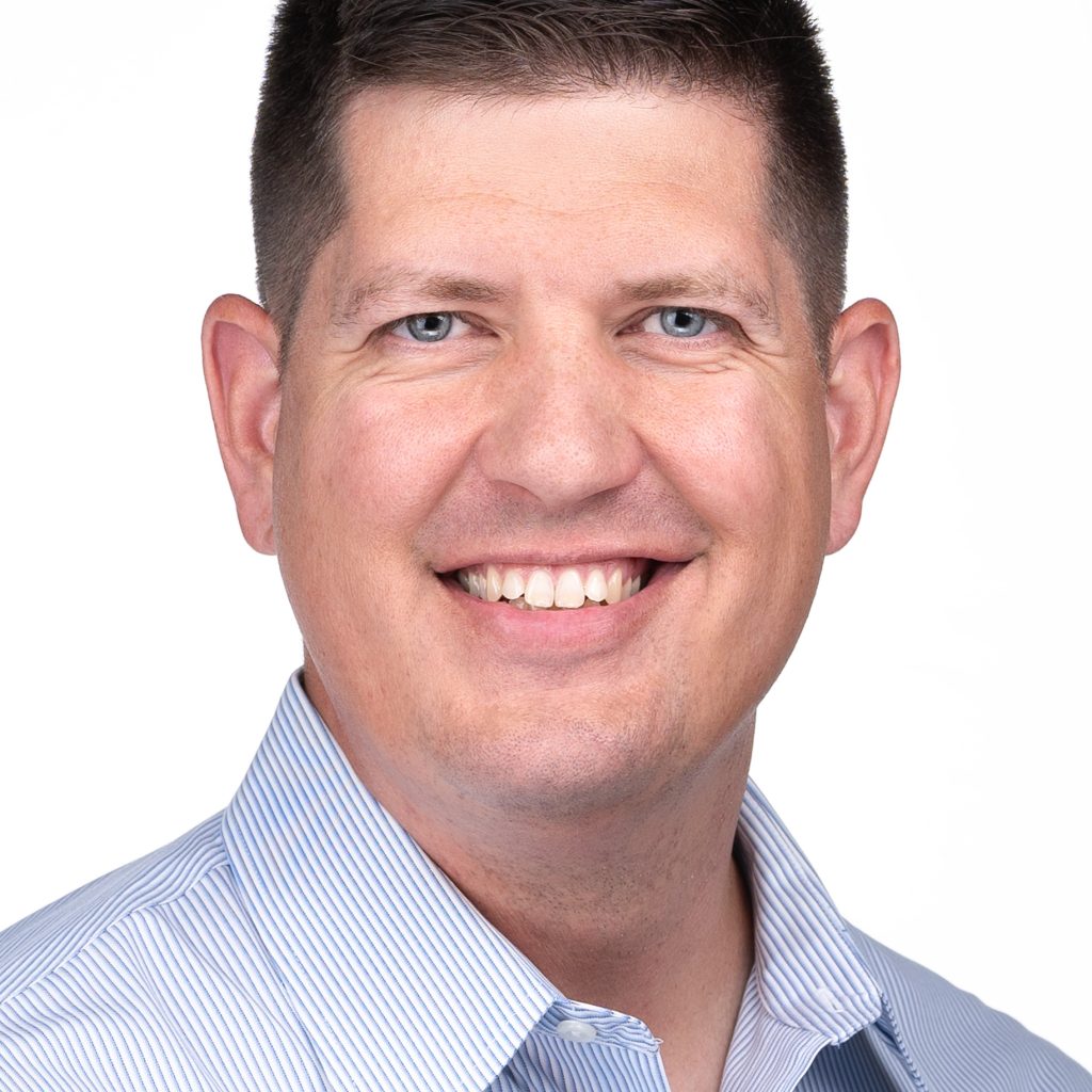 A man in a blue shirt smiling for the camera during a headshot session with Sarah Anne Wilson Photography in Cary, North Carolina.