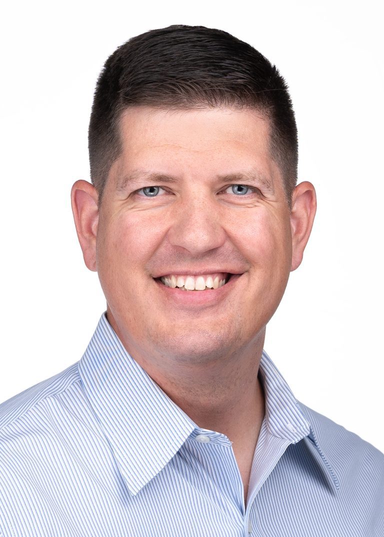 A man in a blue shirt smiling for the camera during a headshot session with Sarah Anne Wilson Photography in Cary, North Carolina.