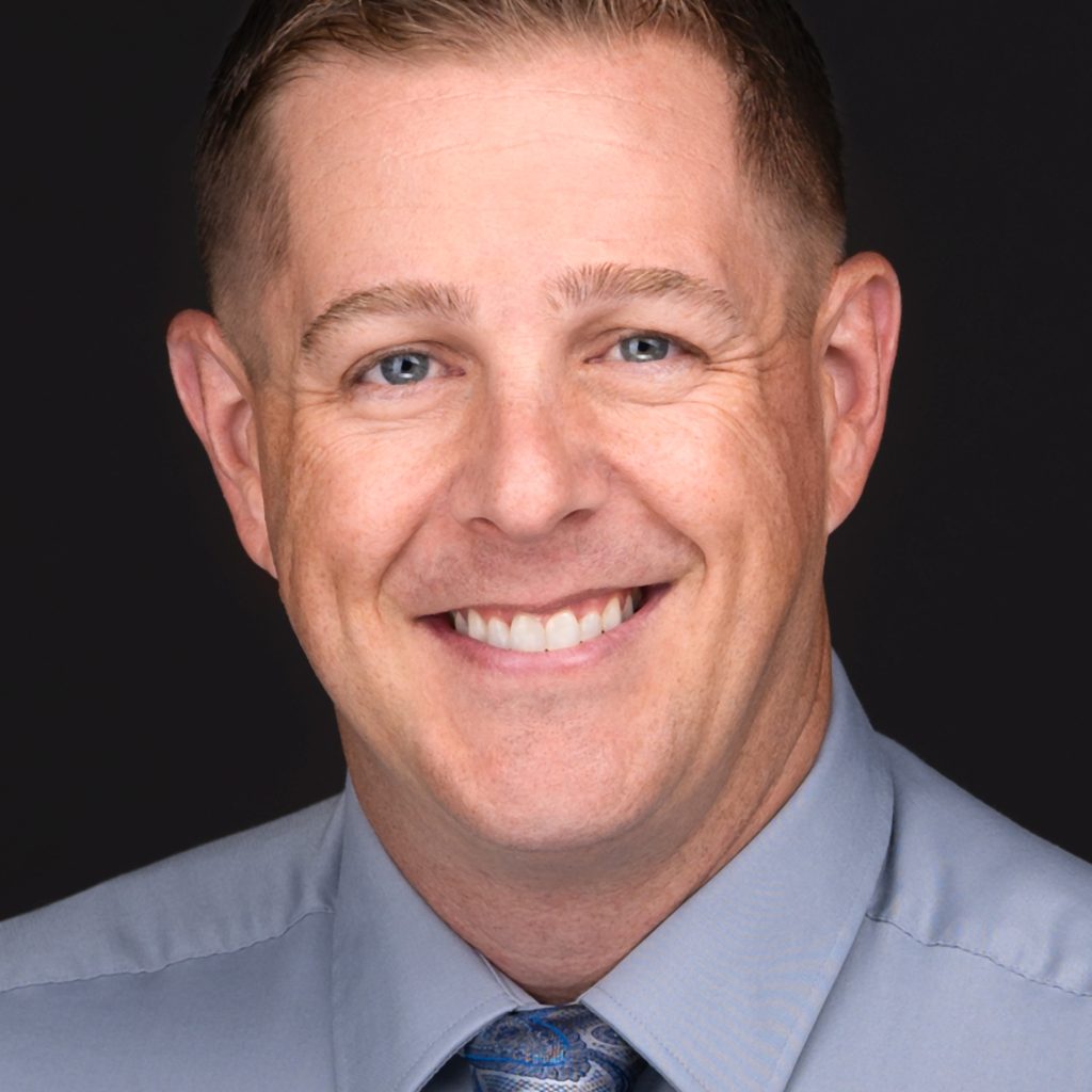 A man in a blue shirt and tie poses for professional headshots captured by a skilled photographer.