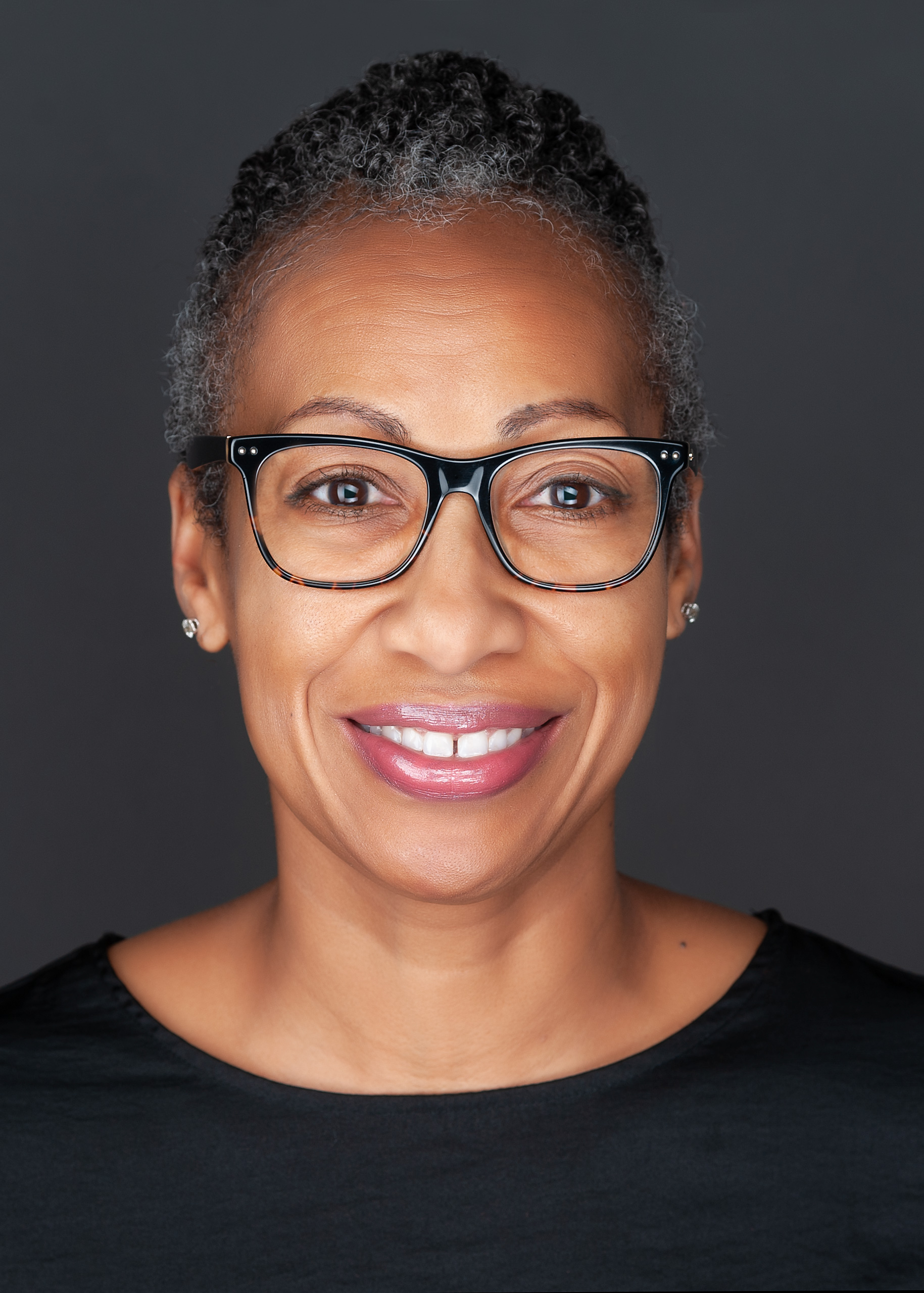 An African American woman in glasses smiles for the camera during her business headshots session with Sarah Anne Wilson Photography near Cary, North Carolina.