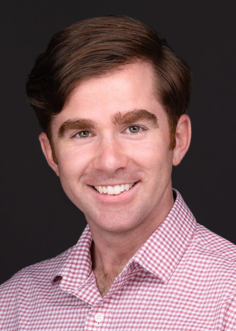 A man with a beautiful smile is wearing a red and white checkered shirt for personal branding photos and poses for Sarah Anne Wilson Photography