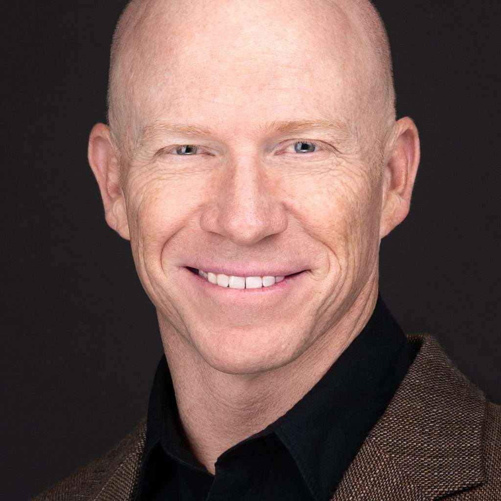 A bald man with a genuine smile poses for a business headshot captured by Sarah Anne Wilson Photography in Cary, North Carolina.