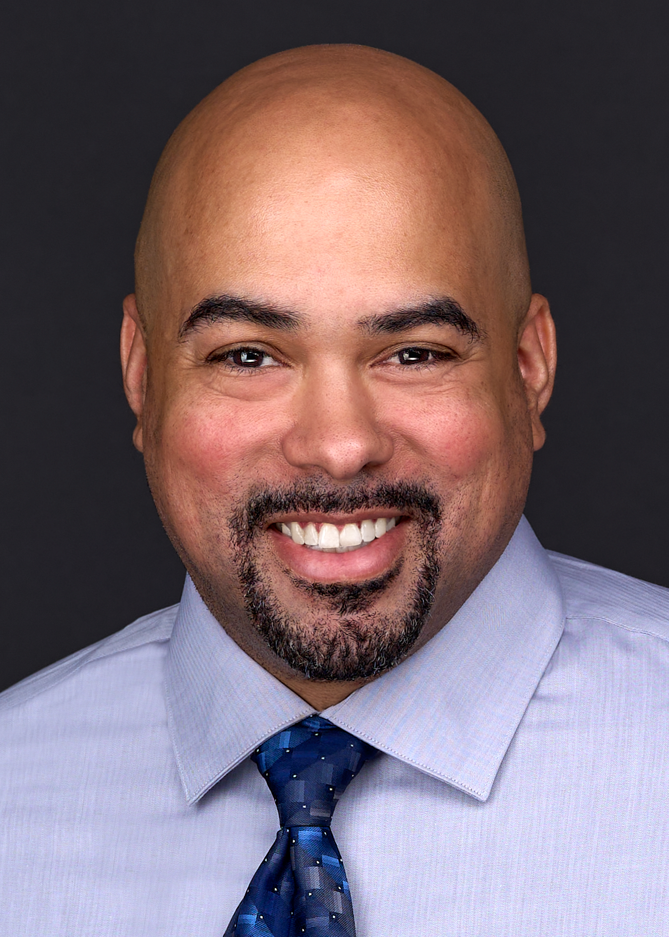 A corporate businessman wears a pastel purple shirt and blue tie as he sits for a professional headshot in the photography studio of Sarah Anne Wilson in Cary NC