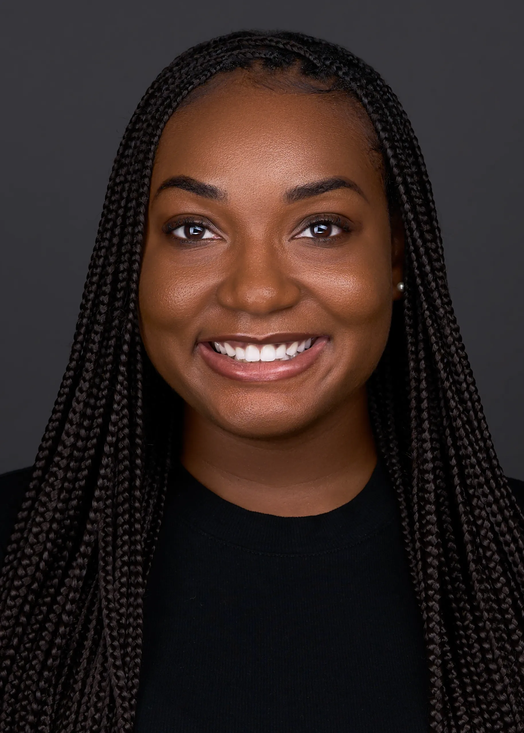 A young lady wearing a black sweater and braids, poses for a online dating profile headshot in Cary NC