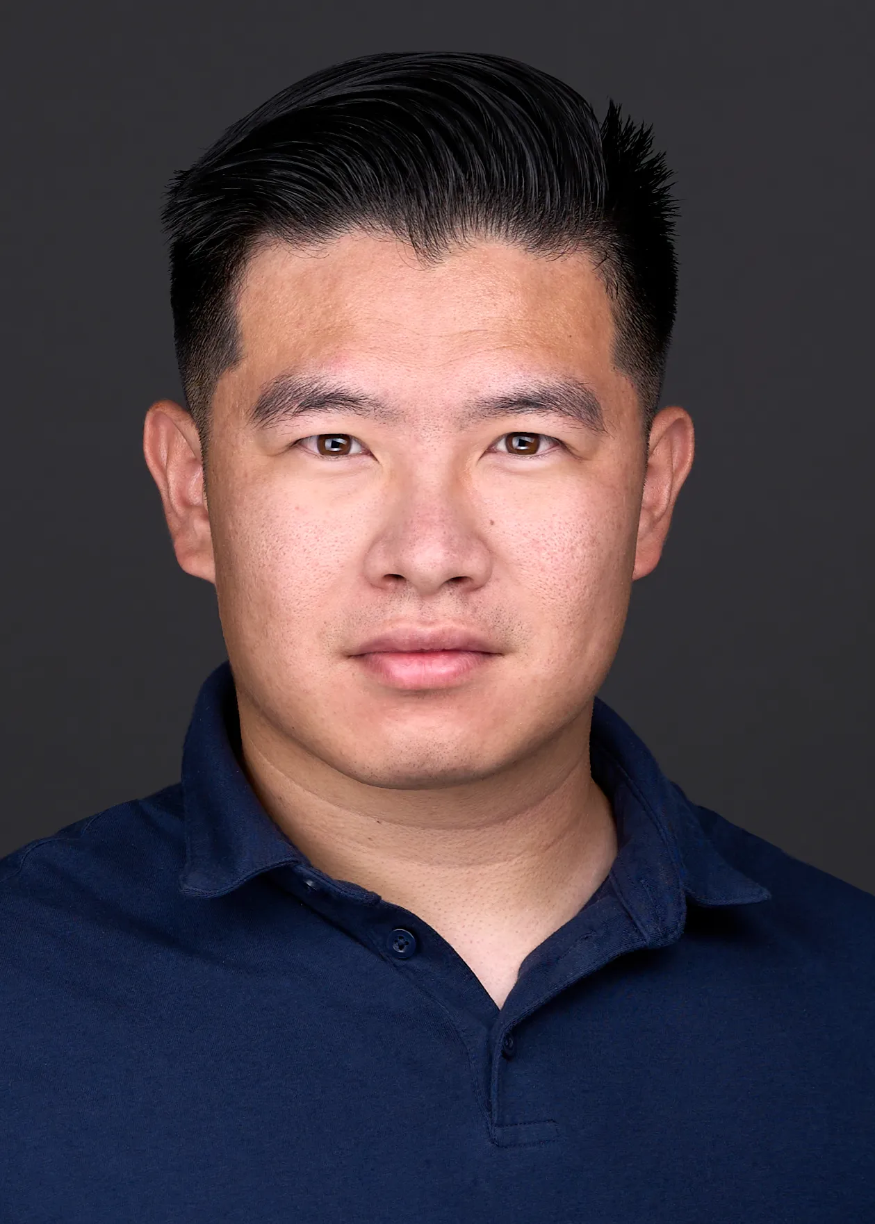 A young man poses for a professional dating headshot wearing a navy polo in Raleigh NC