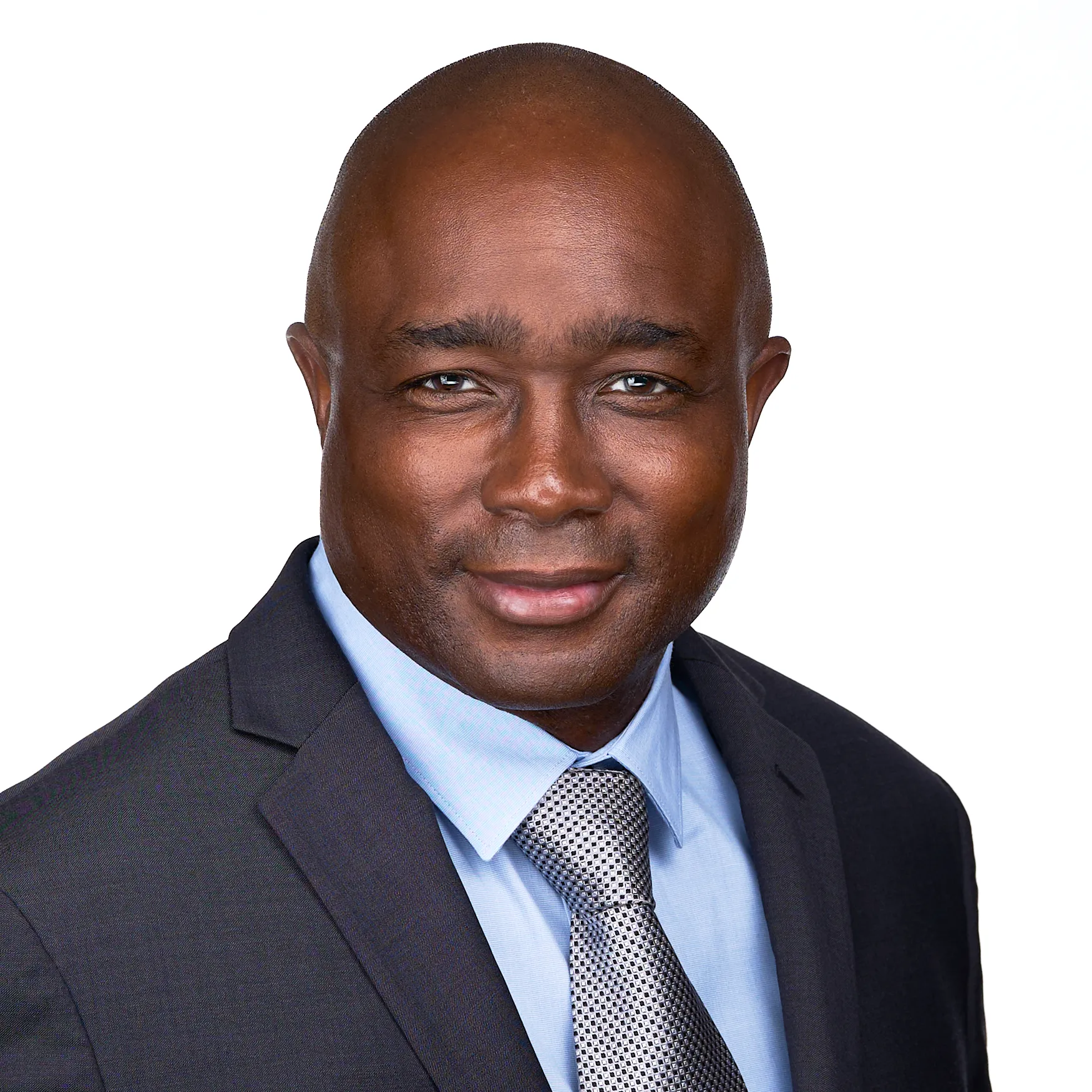 A man in a suit and tie, looking directly at the camera with a neutral expression, stands against a plain white background—an ideal example of professional headshots.