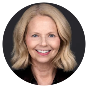 Portrait of a woman with shoulder-length blonde hair, smiling, set against a dark background, perfect for a professional headshot.