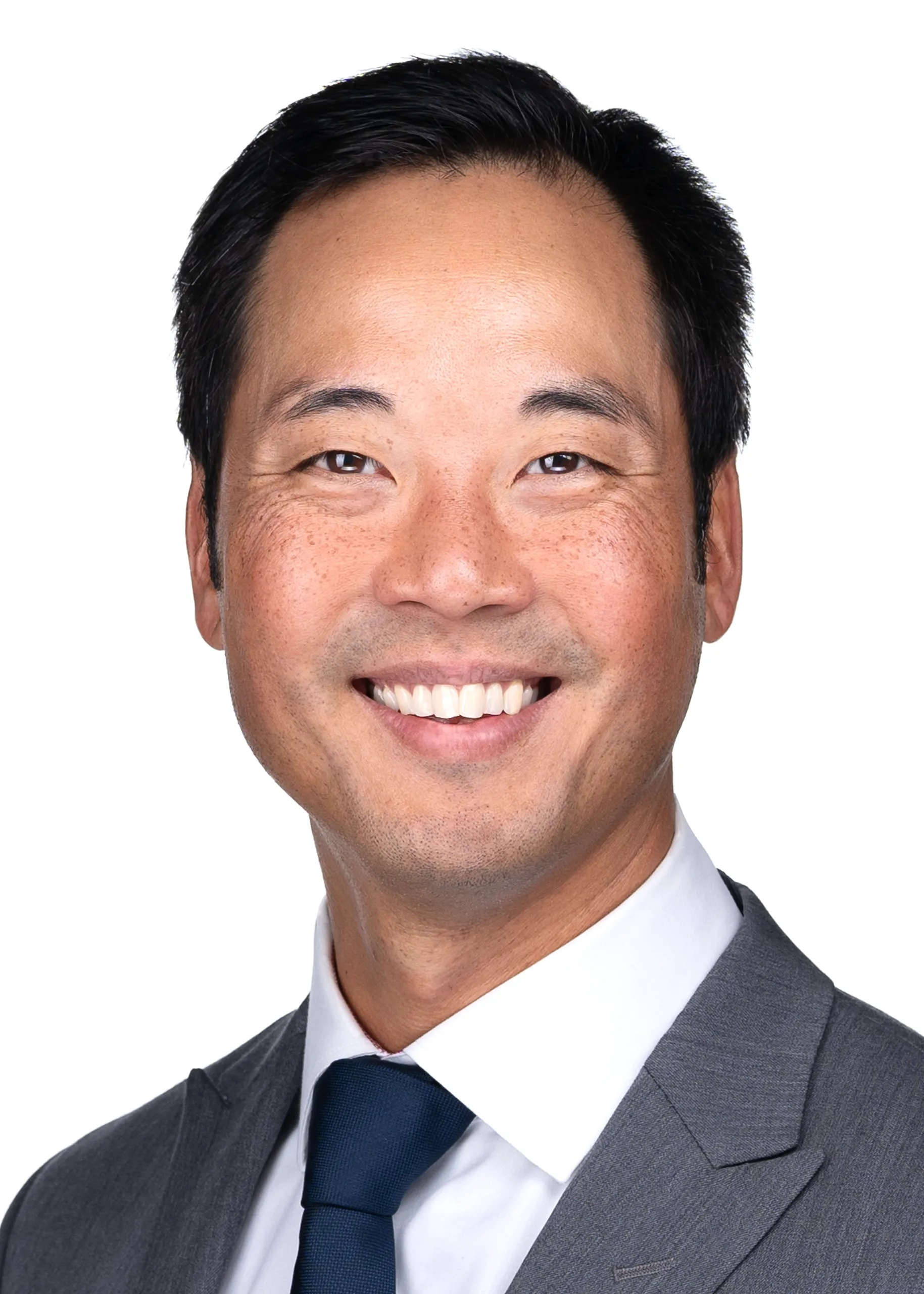 A smiling Asian man in a suit and tie was captured by professional photographer Sarah Anne Wilson Photography in Cary, NC.