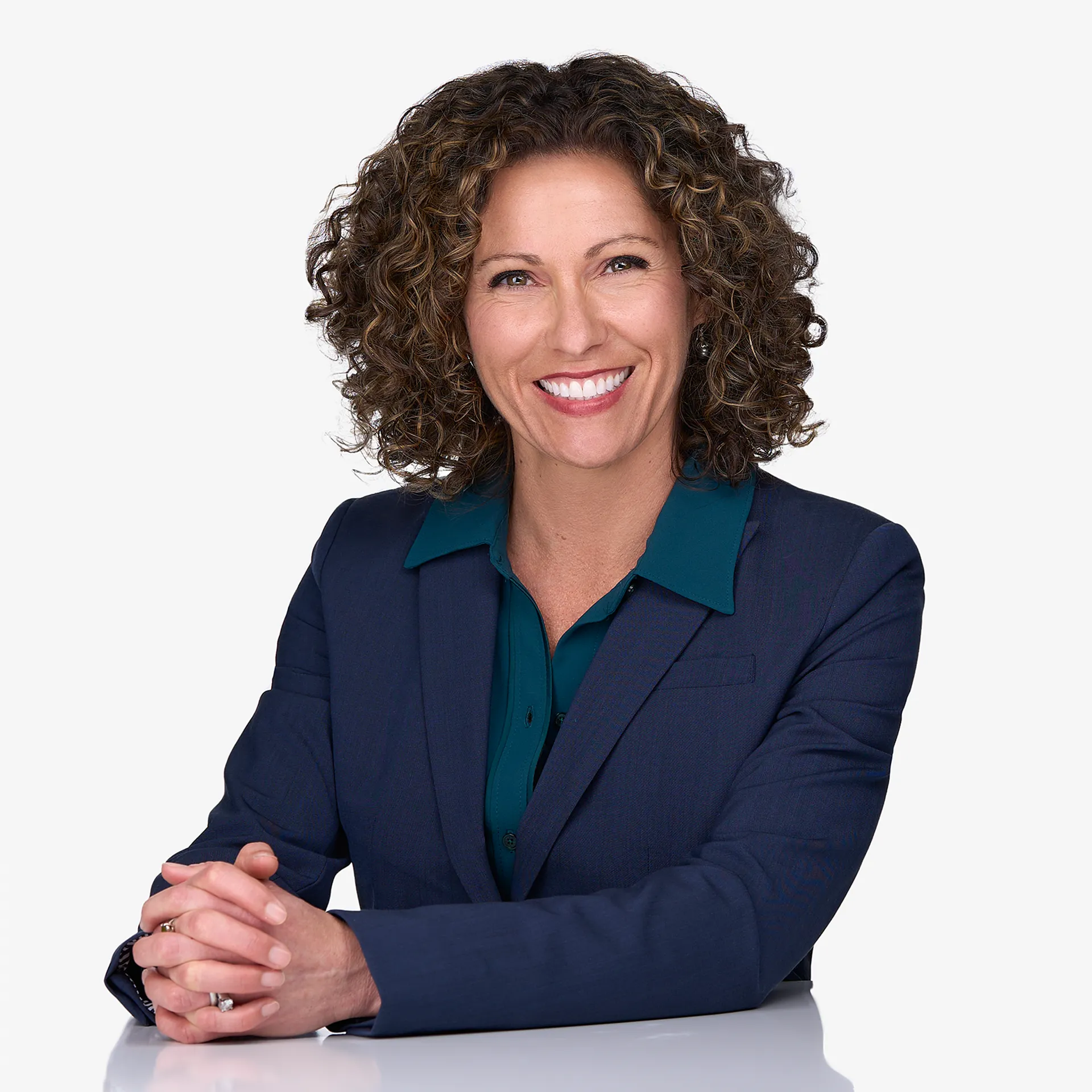 A woman with brown curly hair smiles for the camera while posing for personal branding images at the studio of Sarah Anne Wilson