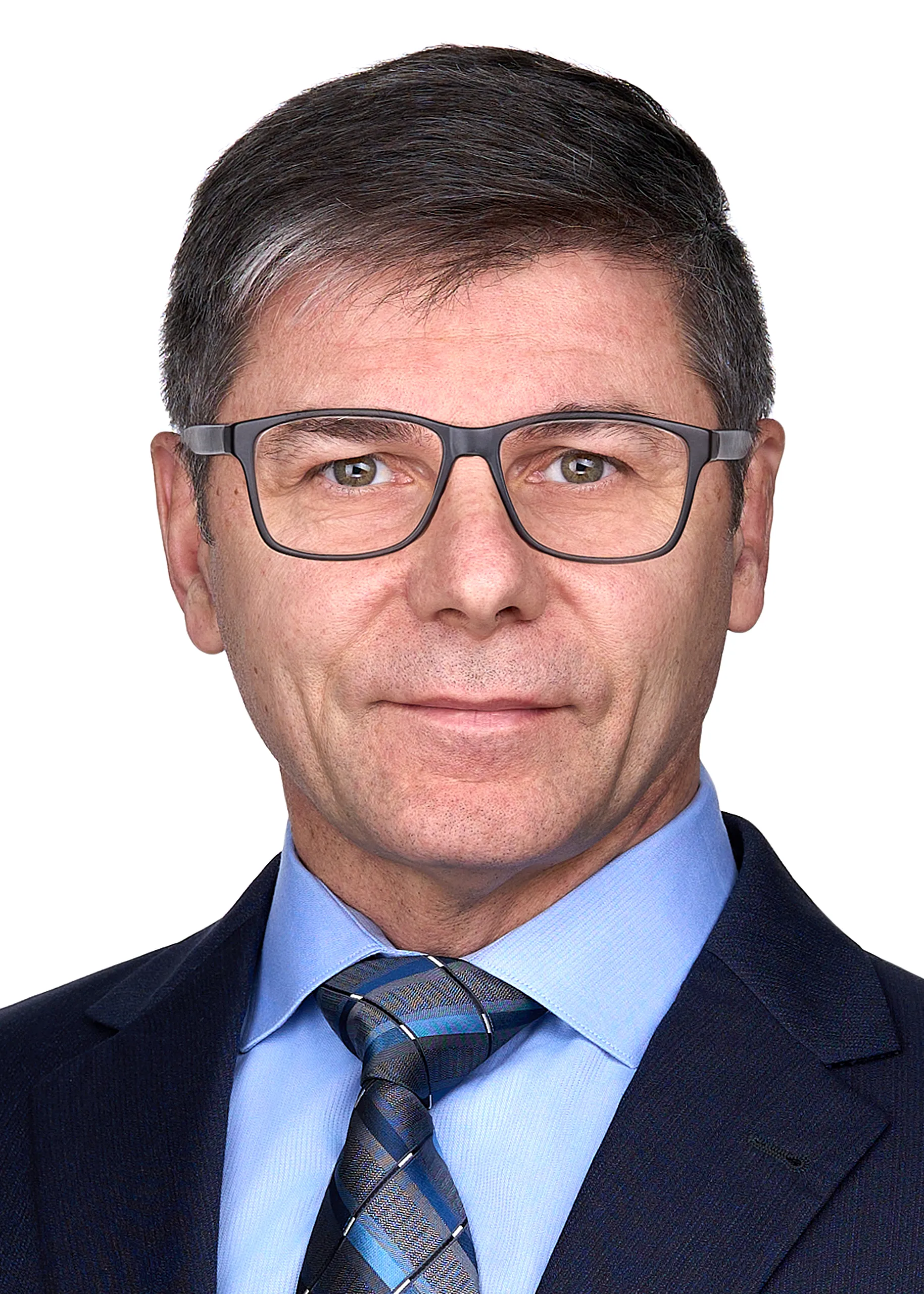 A man wearing glasses, a blue suit poses for a professional headshot with a serious expression in the photography studio of Sarah Anne Wilson Photography