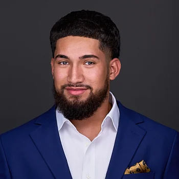 A young man with black hair, a beard and mustache, wears a royal blue blazer with a yellow pocket square in the photography studio of Sarah Anne Wilson Photography in Cary NC