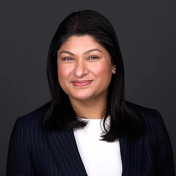 A Hispanic women with black hair wears a blue suit while sitting for a professional headshot in Raleigh NC