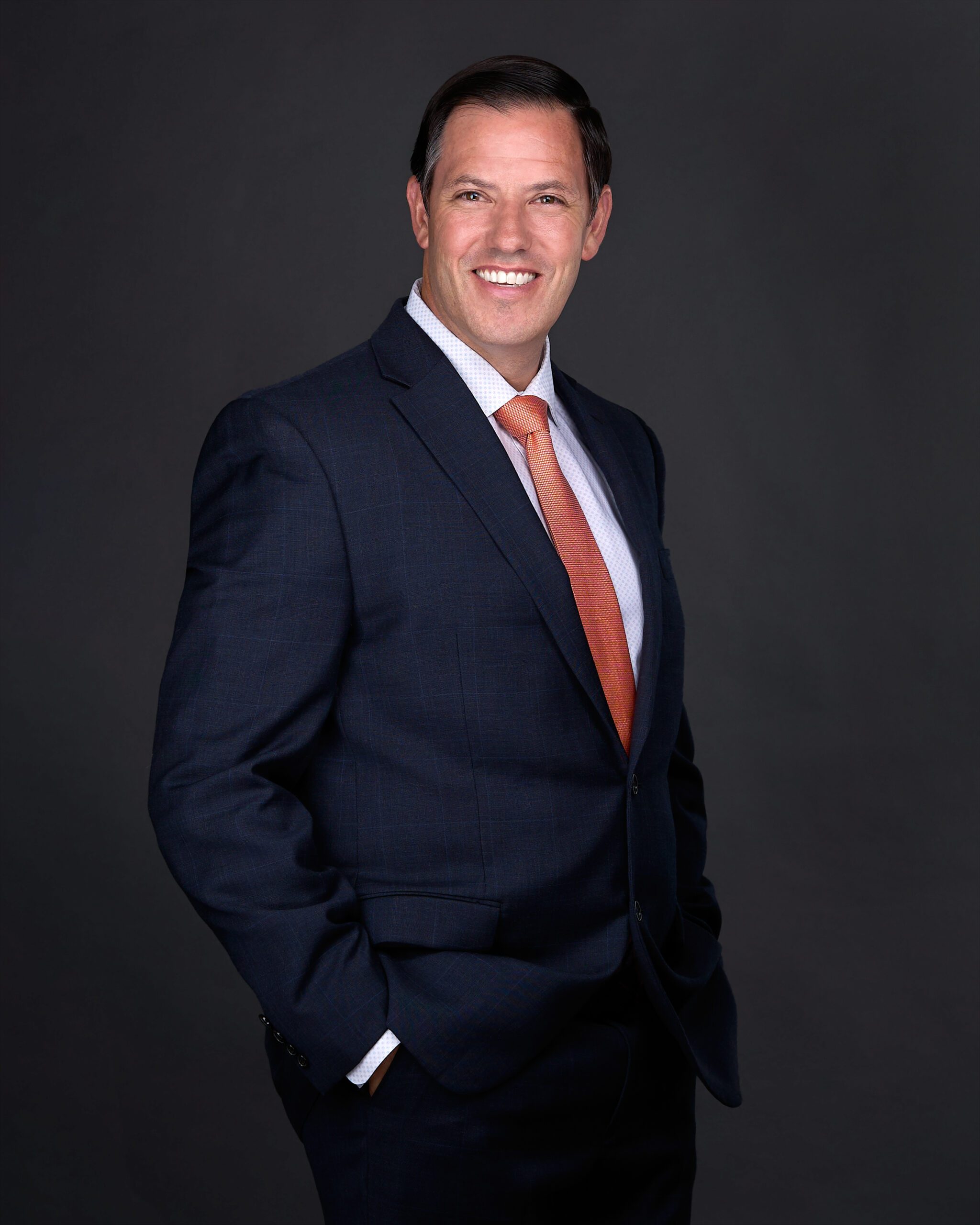 A man in a blue suit poses confidently for a personal branding image taken by a professional photographer in Raleigh NC