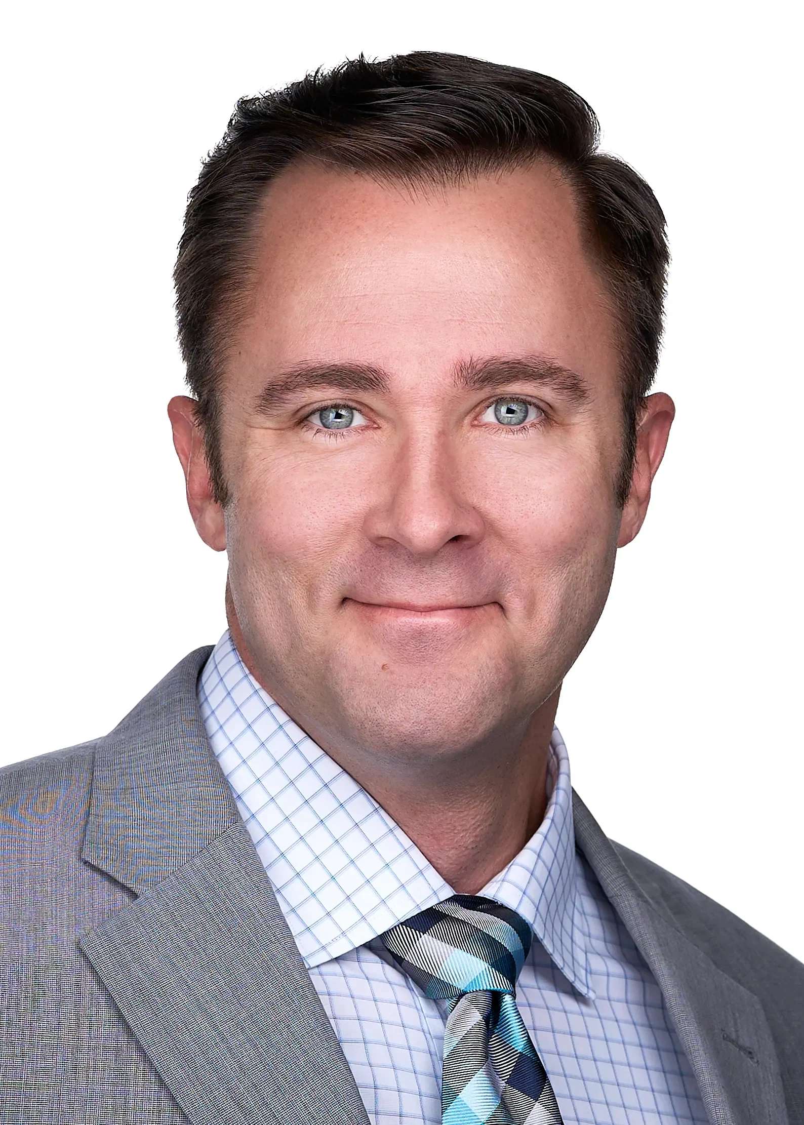 A business professional poses for a headshot wearing a grey suit, plaid tie and striped shirt in a photography studio in Raleigh NC