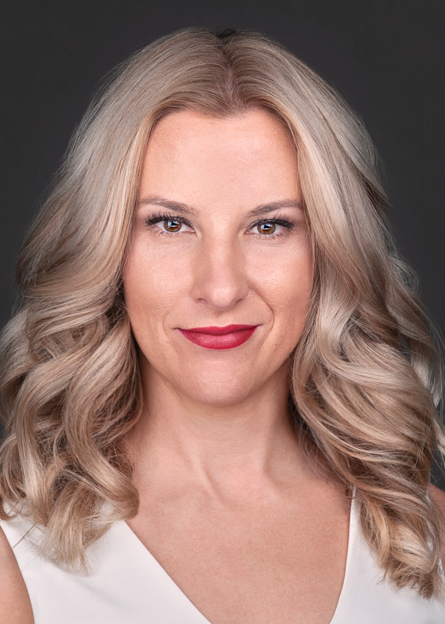 A young woman with long blonde hair and bold red lipstick poses for a personal branding portrait at a photography studio in Cary NC